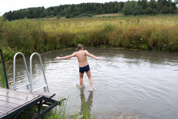 istock Boy jumping from wooden bridge into pond 1348598038