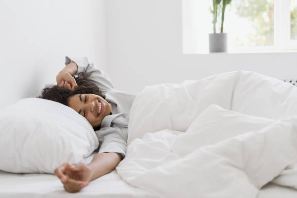 young afro american woman waking up in bedroom - wake up stretching women black imagens e fotografias de stock