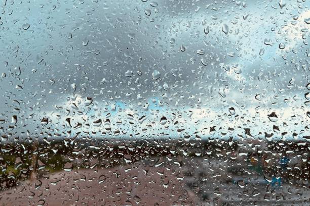 istock Rain drops on the clear glass. Beautiful raining sky with city background. 1348623885