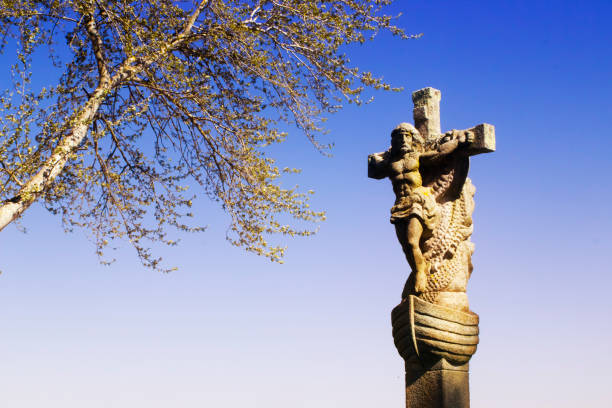 Old cruceiro and leafless tree branches and clear blue sky background in Sada, A Coruña province, Galicia, Spain.
