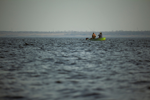 Two fishermen in a boat on the river. Motor boat with fishermen in the middle of the river.