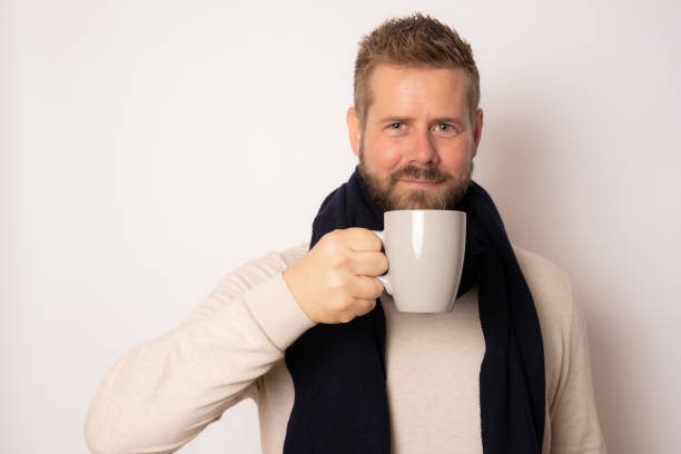 istock Young man warming up with hot tea in wintertime isolated over white background. 1348655029