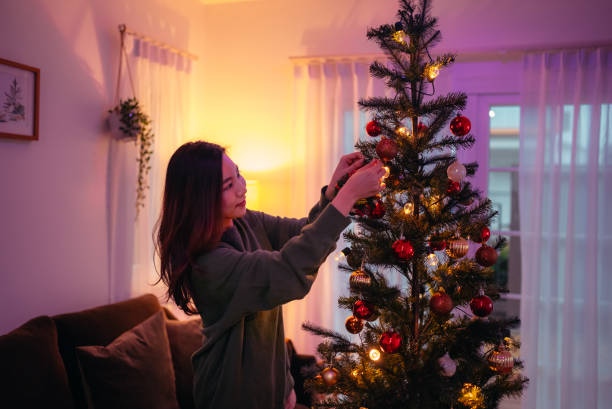istock Young woman decorate Christmas tree. 1348655424
