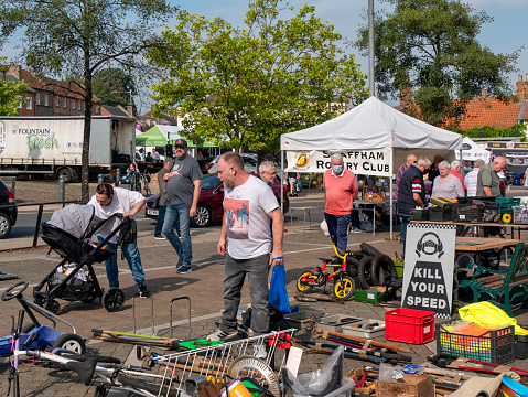 A busy Saturday morning, with people browsing stalls and auction lots on market day in Swaffham, in Norfolk, Eastern England. The regular Saturday market and auction is a traditional event in Swaffham, a small market town in a rural area. Some people are wearing face masks as the coronavirus pandemic is still active.