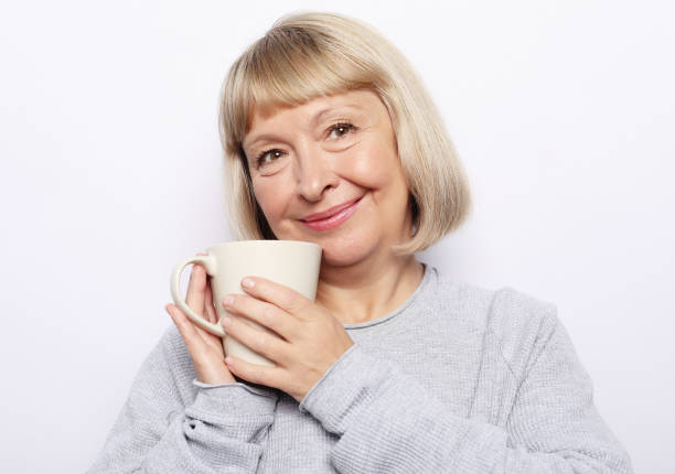 istock Happy old lady with coffee, isolated on white 1348667459