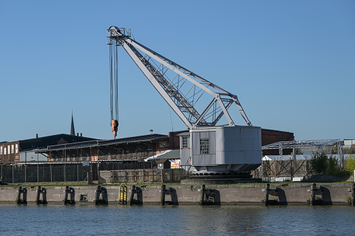 Historical harbor crane from 1893 at the docks in the city port of Luebeck on the river Trave, blue sky with copy space, selected focus