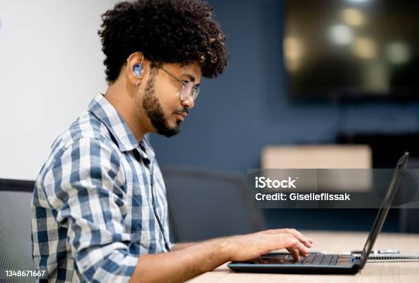 Hearing Impaired Man Working On Laptop At Office Stock Photo - Download Image Now - Hearing Aid, Deafness, Hearing Loss
