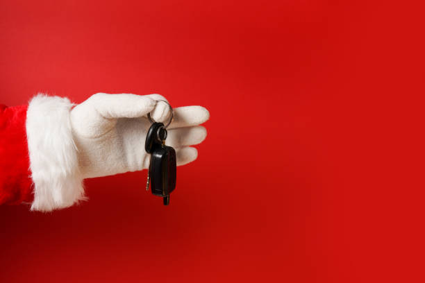 istock Santa claus holding car key on red background, copy space 1348671800