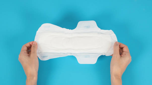 istock Hand is holding Sanitary napkin with wings for night use on blue background. 1348676803