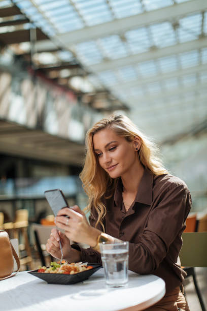 istock Beautiful woman checking her phone and having salad 1348677361