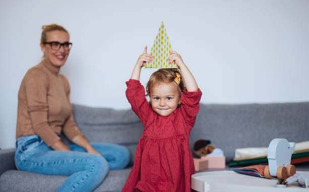 wesoła dziewczyna w czerwonej sukience dekorująca dom na boże narodzenie - standing family golf loving zdjęcia i obrazy z banku zdjęć