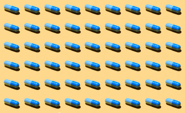 istock Pills pattern. Set of blue tablets isolated on yellow background. Pattern made with pharmaceutical medicine capsules on yellow background. Medicine concept. 1348681055