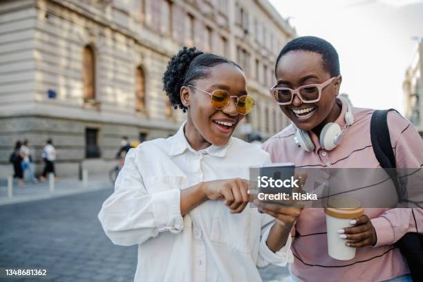 Two Woman In The City Looking At The Phone And Smiling Stock Photo - Download Image Now