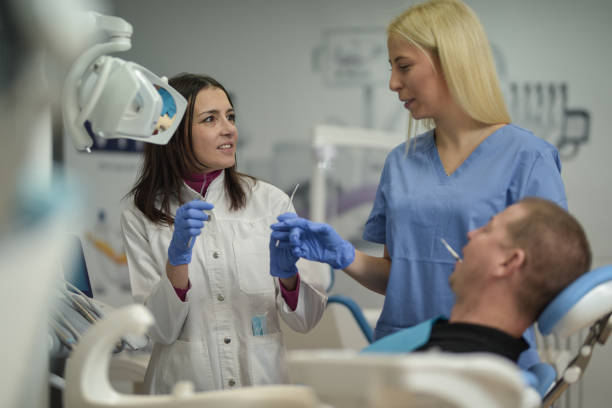 istock Dentist with her assistant doing dental check at the patient in dentist office 1348693763