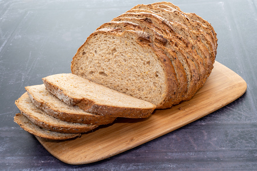 A sliced loaf of spelt bread placed on a dark background