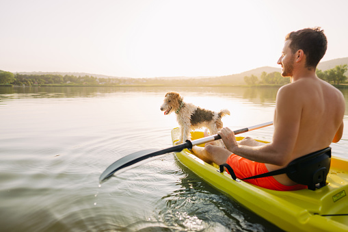 Photo of a man kayaking on the lake with his dog
