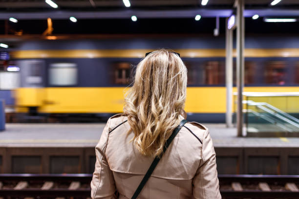 istock Woman looking to passing train in railway station at night 1348708383