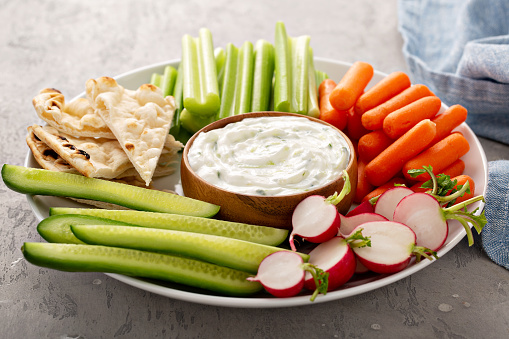 Large snack board with tzatziki dip made with yogurt and cucumber with fresh vegetables and pita