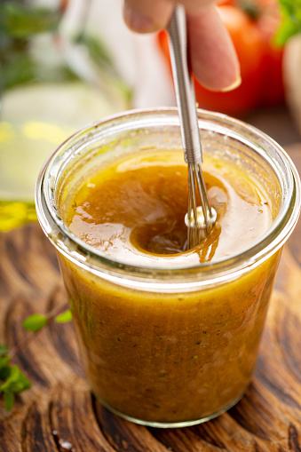 Mixing homemade vinaigrette salad dressing with olive oil, vinegar and herbs
