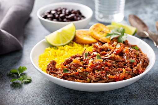 Ropa vieja, traditional flank steak dish with rice, cuban beans and plantains