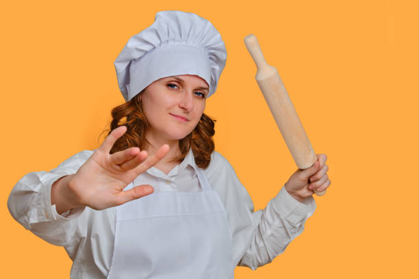 istock Happy woman chef with dough rolling pin in hand on studio background, copy space 1348717049