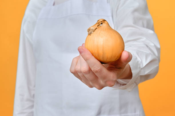 istock Man chef with onion in hand on studio background, copy space 1348717061