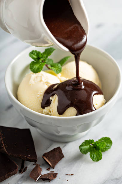 наливание шоколадного соуса на мороженое - chocolate topping стоковые фото и изображения