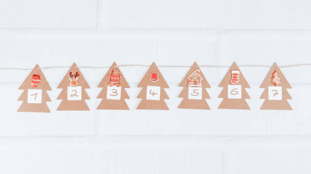sete árvores artesanais com números 1,2,3,4,5,6,7 em um fio de juta e uma decoração de natal pendurada no meio em uma parede de tijolos brancos - december 7th - fotografias e filmes do acervo
