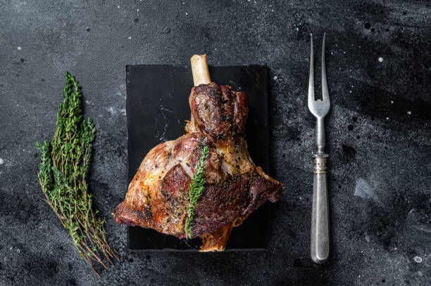 istock Oven Roasted lamb mutton whole leg with thyme. Black background. Top view 1348752558
