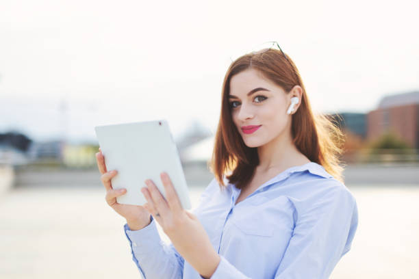 istock Happy young redhead businesswoman using tablet outdoors 1348754774