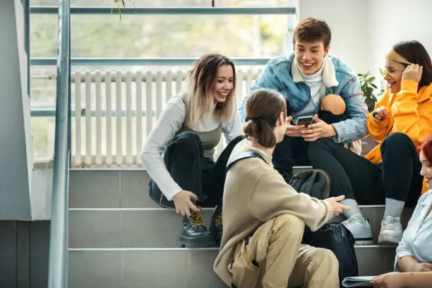 Closeup front view of a group of high school students on a break sitting on hallway stairs.