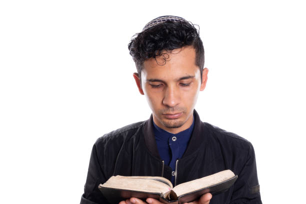 lateinischer mann, der das judentum isoliert auf weißem hintergrund praktiziert. junger mann mit kippa liest bibel. - talmud stock-fotos und bilder