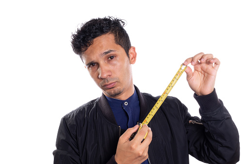 Man showing tape measure, white background. Young latino man showing how to use a tape measure.