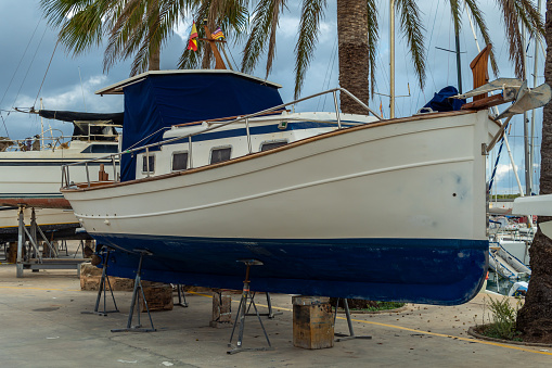 Recreational boat supported on metal tripods for future restoration. Sa Rapita marina, island of Mallorca, Spain