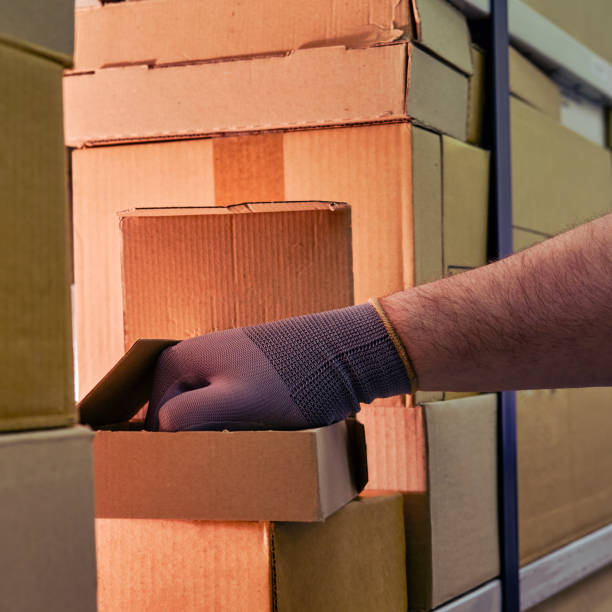 istock Theft from a box in a warehouse when sending goods by mail, hand in glove 1348769394
