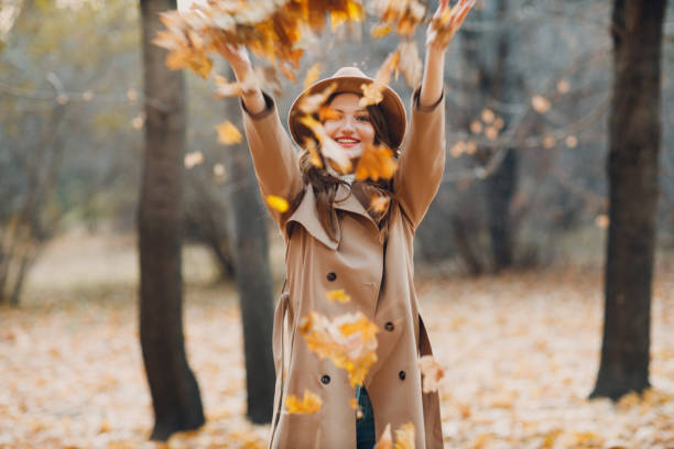 Young woman model in autumn park with yellow foliage maple leaves. Fall season fashion. stock photo