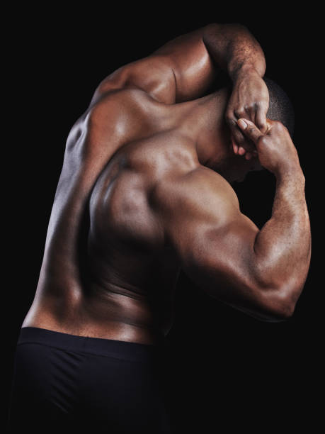 istock Rearview studio shot of a fit young man flexing against a black background 1348772396