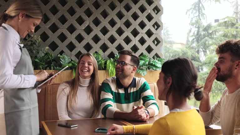 Young adults telling their orders to the waitress.