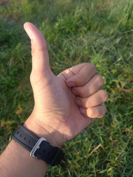istock Man left hand showing thumb on grass park 1348816332