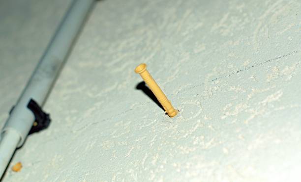 istock A yellow dowel is hammered into the white wall 1348820285