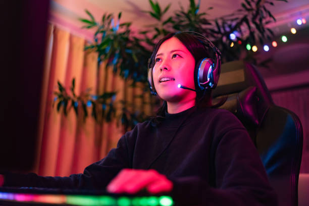 молодая женщина в прямом эфире во время игры в многопользовательскую онлайн-игру в гостиной дома - pc game стоковые фото и изображения