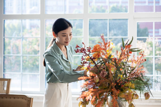 istock Woman arranging flowers at home 1348827631