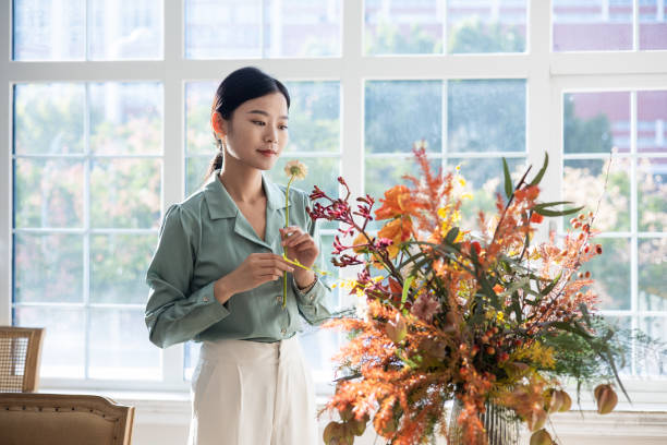 istock Woman arranging flowers at home 1348827635