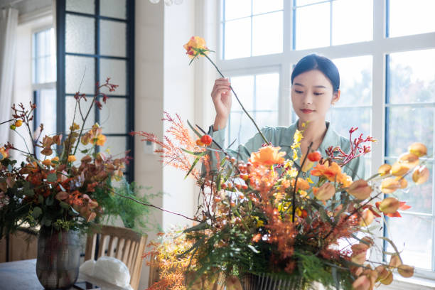 istock Woman arranging flowers at home 1348828143