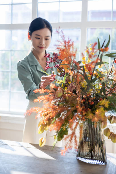 istock Woman arranging flowers at home 1348828145