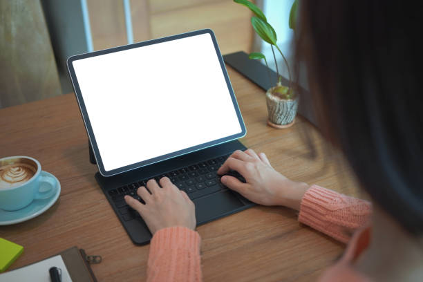 istock View over shoulder young woman using computer tablet on wooden table. 1348828532