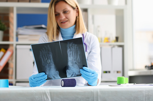 La doctora examina una radiografía de la pierna del paciente photo