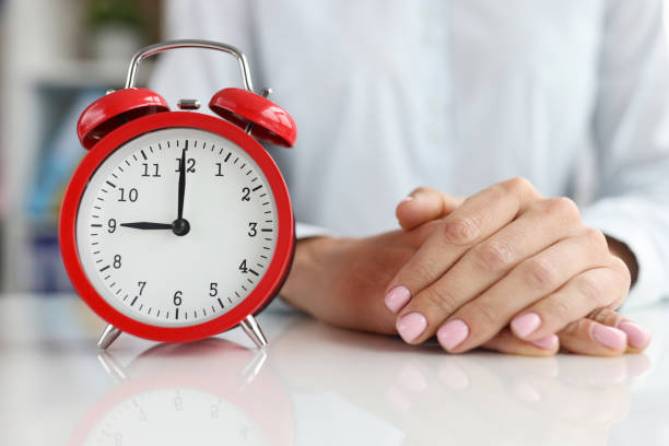 red alarm clock at nine in morning and the businessman sits with folded arms at table - clock clock hand antique clock face imagens e fotografias de stock