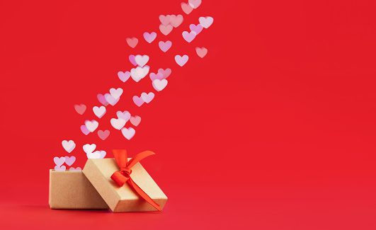 open gift box with flying out hearts on red background with place for text