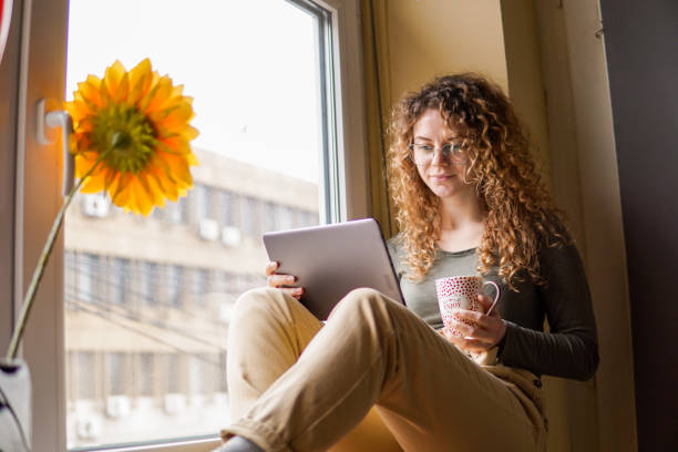 istock Woman using a tablet at home, drinking coffee 1348835911